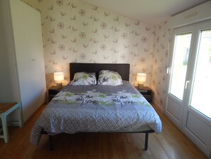 Een slaapkamer met een bed, twee bedlampen, een houten bankje en bloemenbehang.