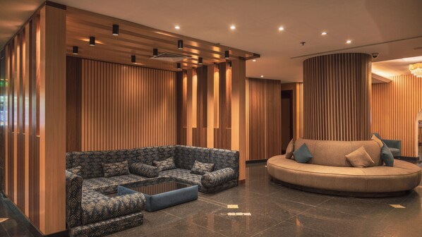 Un interior moderno con un sofá modular, una zona de estar circular y paneles de madera.