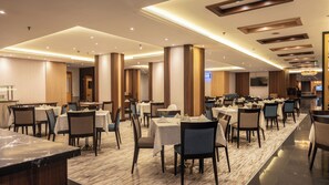 A hotel dining area with multiple tables, chairs, and a long counter. - Vercure Jeddah Alhamra Hotel (Jeddah)
