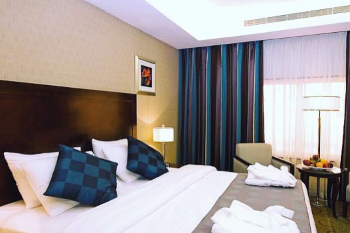 Una habitación de hotel con una cama grande, un escritorio, una silla y una mesa con fruta.