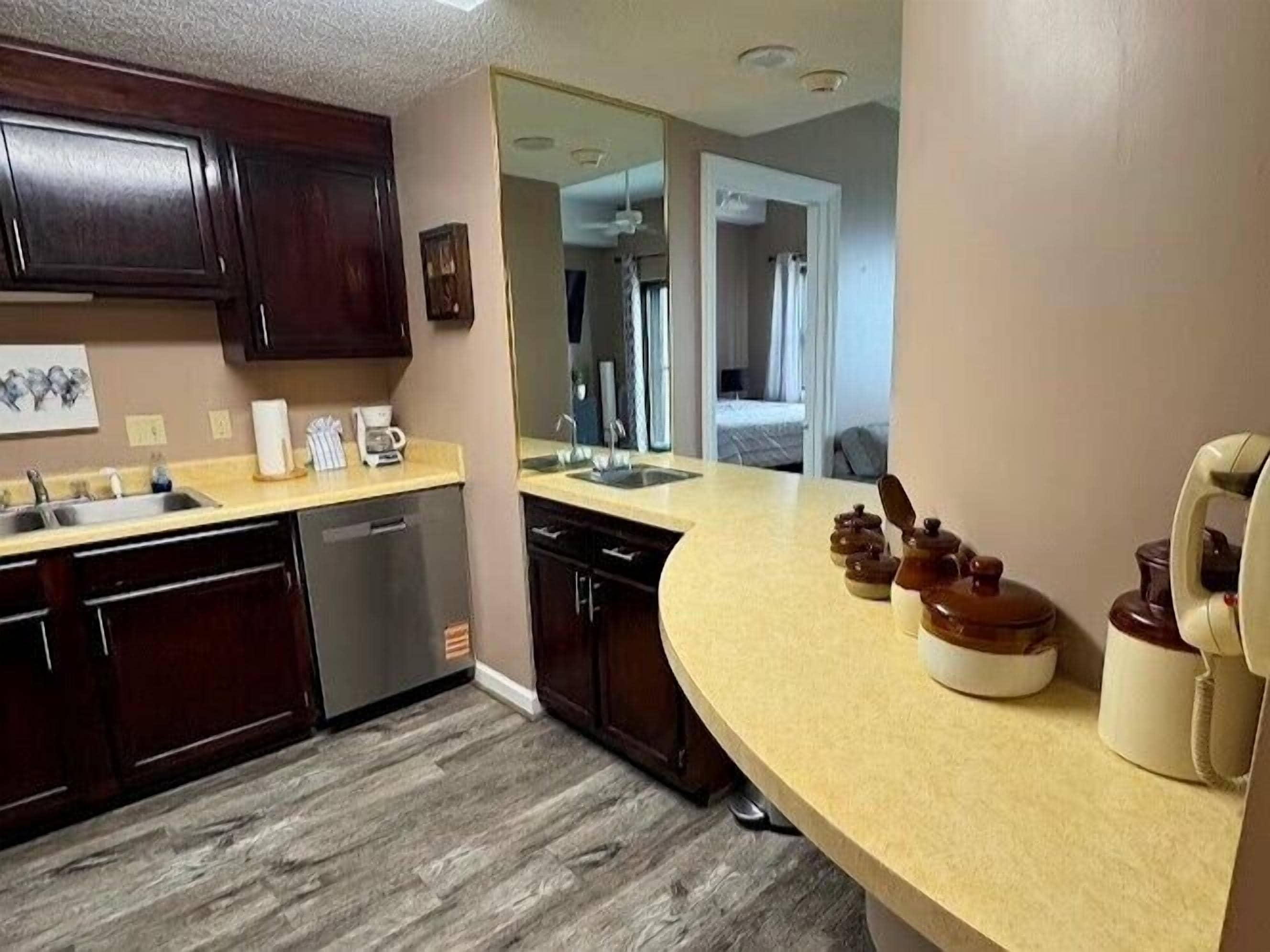 A kitchen with dark wooden cabinets, a beige countertop, and a dishwasher.