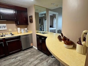 A kitchen with dark wooden cabinets, a beige countertop, and a dishwasher. - 2bd Condo- 8th floor-stunning mountain views- hot tub (Sugar Mountain)