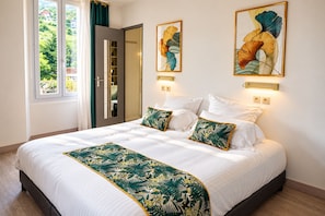 Un dormitori d'hotel amb un llit gran, dues làmpades subjectes a la paret i dues quadres florals emmarcades.