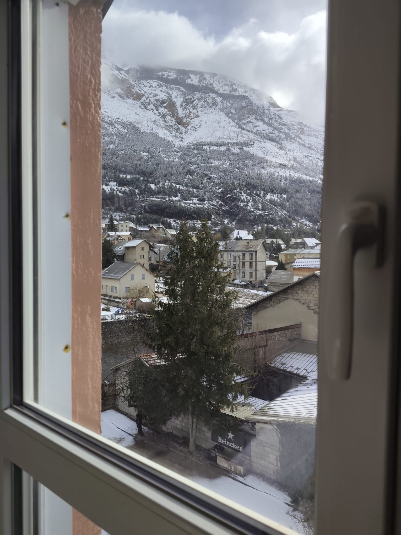 Vista de un pueblo con edificios cubiertos de nieve y montañas al fondo.