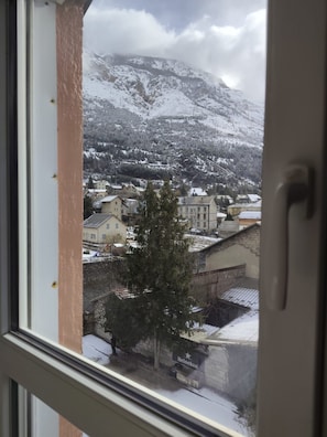 Vista d'una població amb edificis coberts de neu i muntanyes al fons.