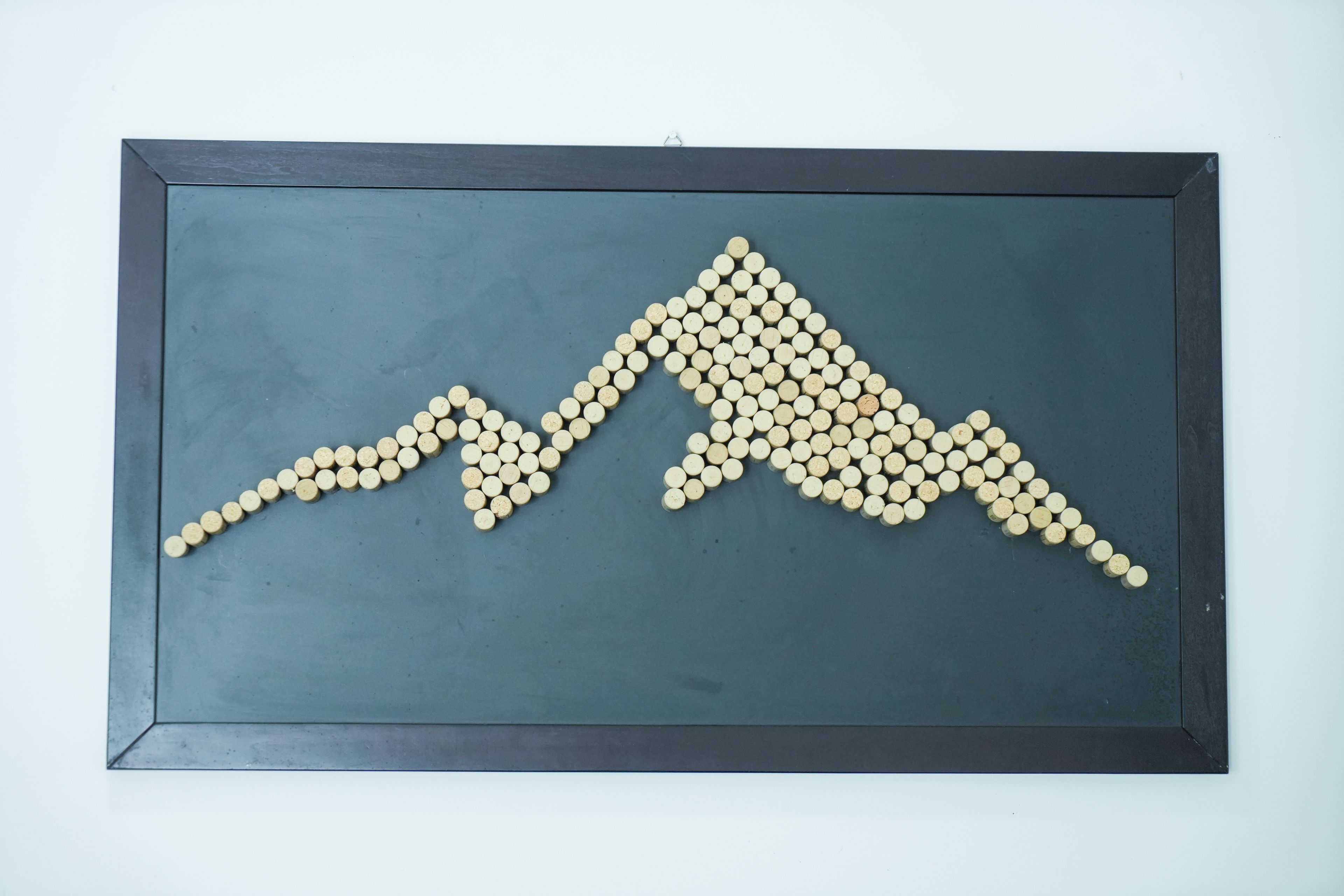Una obra de arte enmarcada con un diseño que recuerda a una montaña, hecha con objetos circulares.