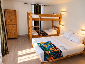 A room with a bunk bed, a wardrobe, and a bed with a colorful blanket.