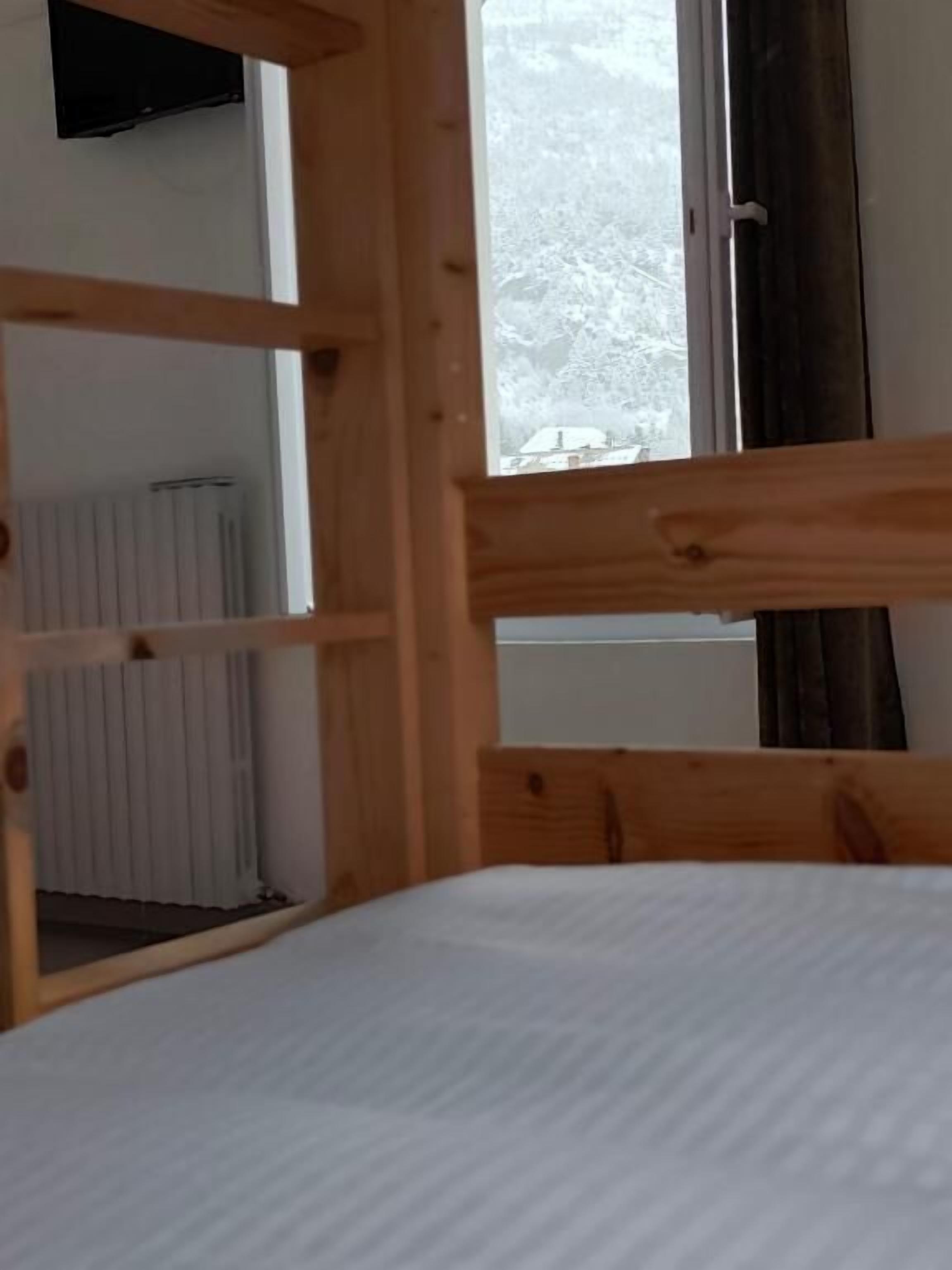Una cama individual con vista a un paisaje nevado a través de una ventana.