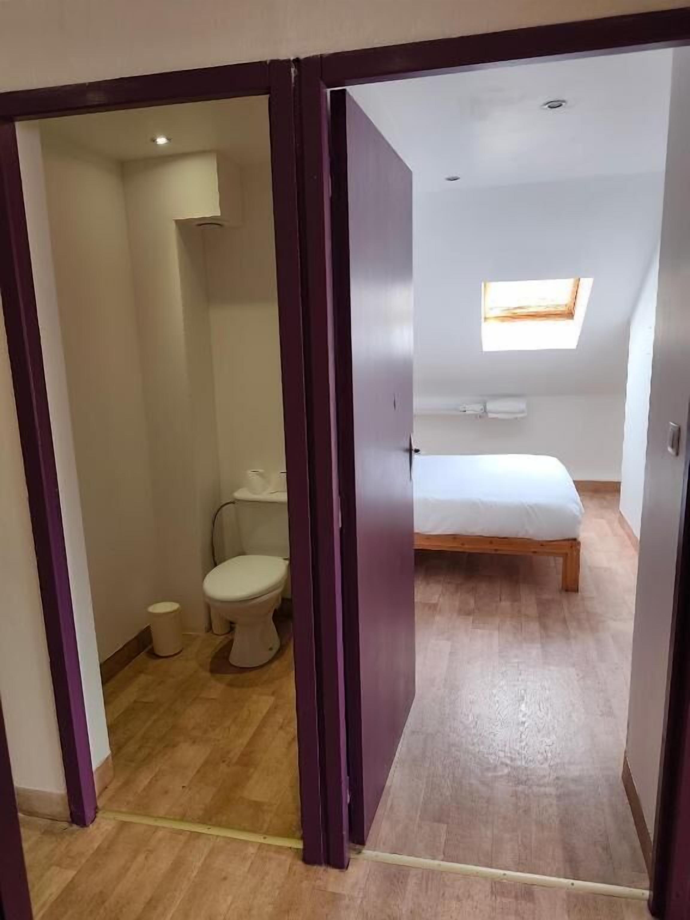 A room with a bed, a window, and a toilet.