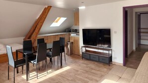 Una sala de estar moderna con comedor, televisor y dormitorio entrepiso con tragaluz.