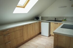 A kitchen with wooden cabinets, a white refrigerator, a microwave, a sink, and a skylight. - Ice Rock Brasil - Hôtel et restaurant Brésilien (L'Argentière-la-Bessée)