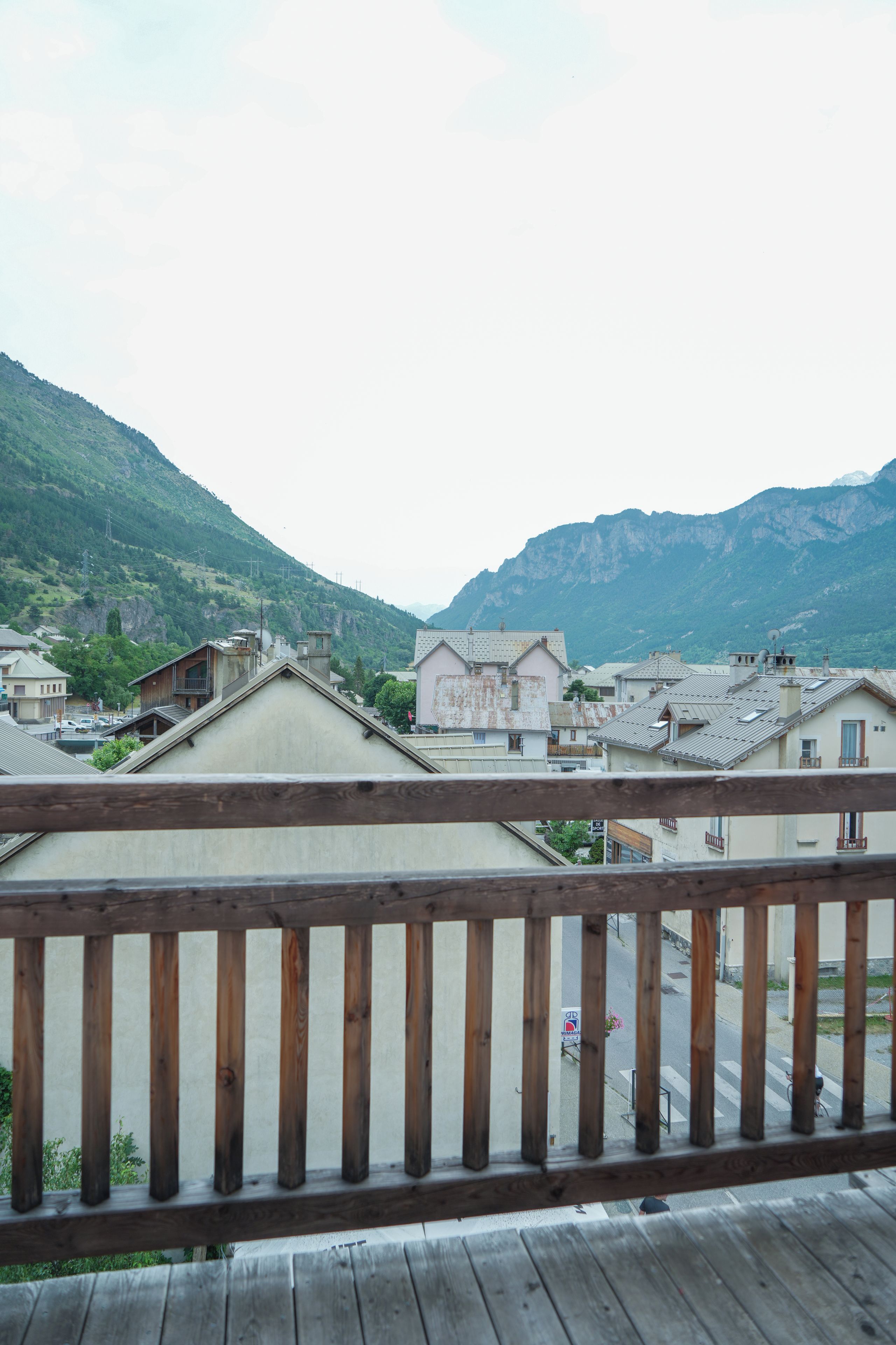 Barandilla de madera con vistas a un pueblo con edificios tradicionales y montañas al fondo.