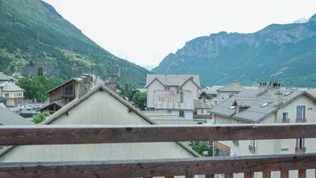 Barandilla de madera con vistas a un pueblo con edificios tradicionales y montañas al fondo.