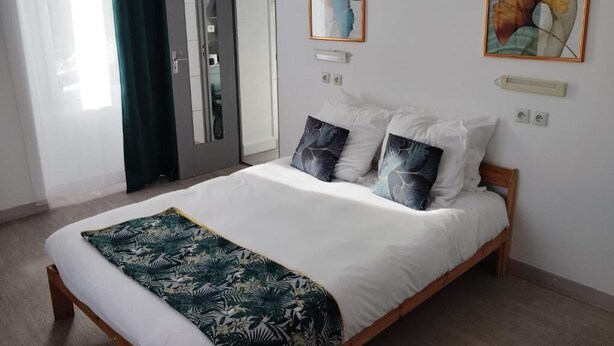 Un dormitorio con una cama, un espejo y dos cuadros en la pared.