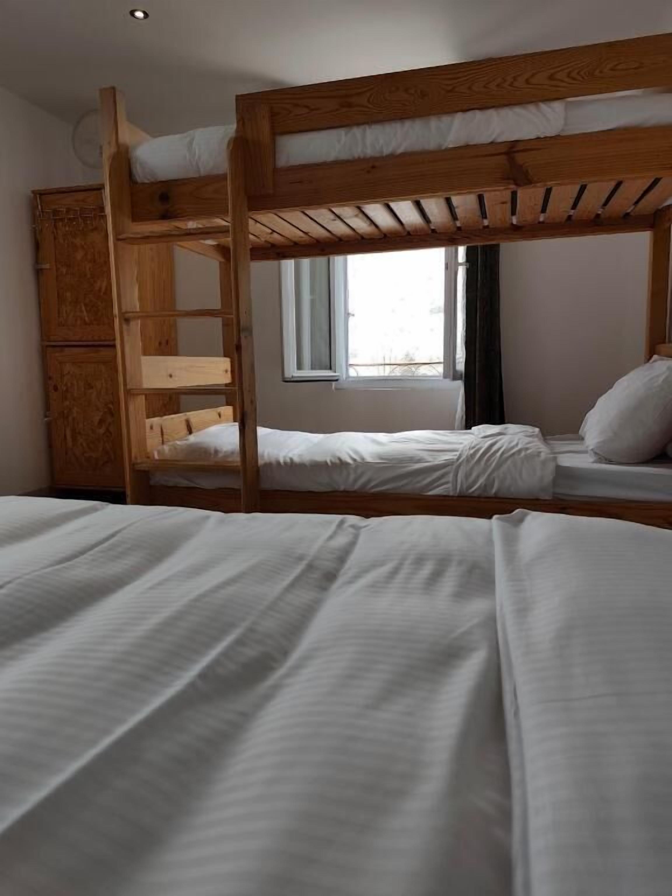 Habitación con literas de madera, una litera inferior y un armario.