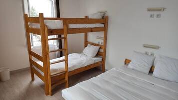 A bunk bed room with a window, a single bed, and a wall-mounted light fixture.