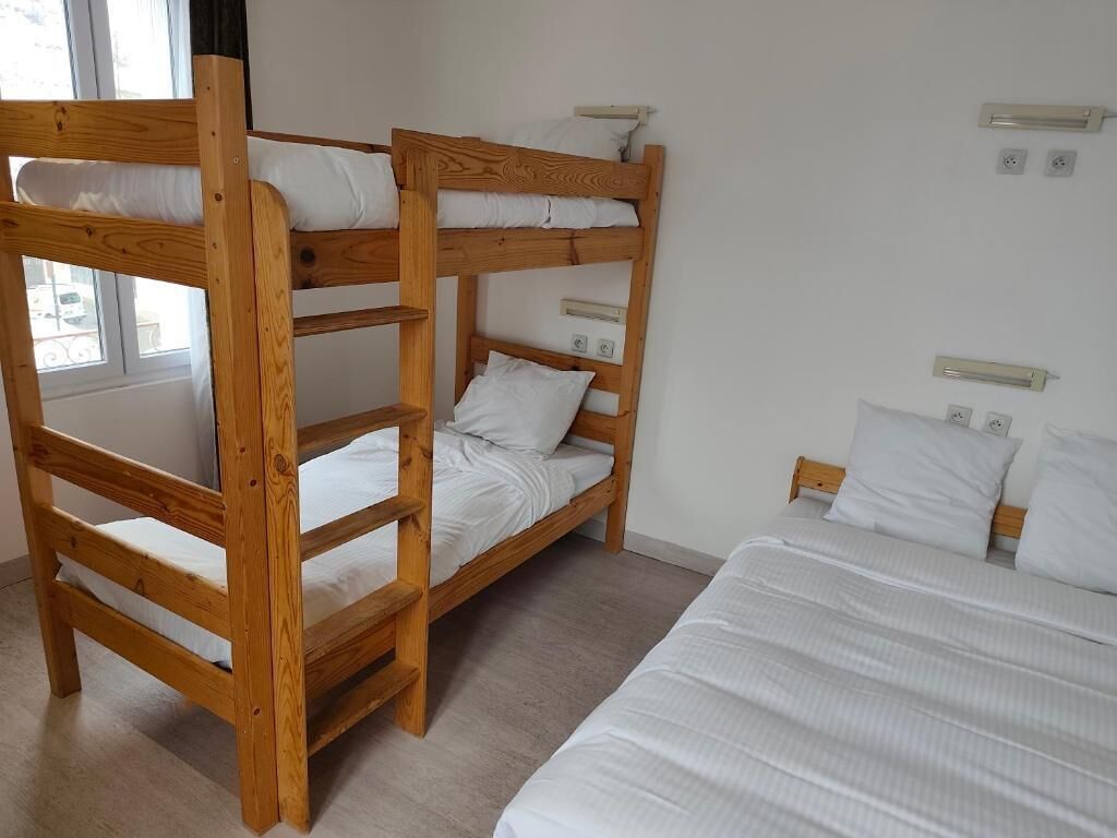 A bunk bed room with a single bed and a window.