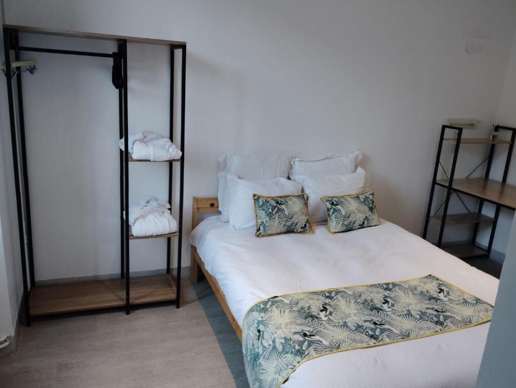 Un dormitorio con cama, almohadas, una colcha, un armario y un escritorio.