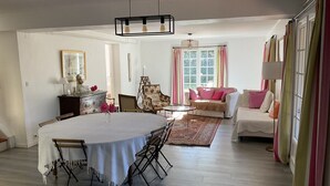 Un comedor con mesa y sillas, un sofá, una butaca, un tapete y una ventana con cortinas.