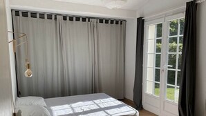 Una habitación con una cama, una ventana con cortinas y una puerta.