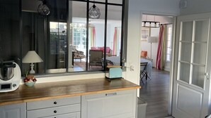 Una cocina con mostrador de madera, un tostador, una tetera y un bol de fruta.
