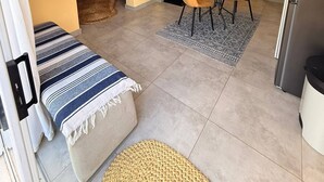 A compact living space with a sofa, dining table, chairs, a refrigerator, and a kitchen area.