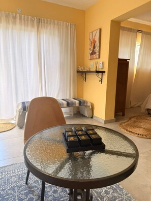A dining area with a round glass table, a sofa, and a wall-mounted shelf with a 'Relax' sign. - Charming Holiday House in Durban North - Your Perfect Getaway Awaits (Durban North)