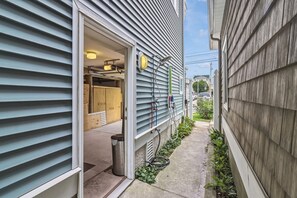 A narrow alleyway with a building entrance, a visible trash can, and a hose on the ground. - Downtown 3BR Top-Floor Condo w/ Balcony (Ocean City)