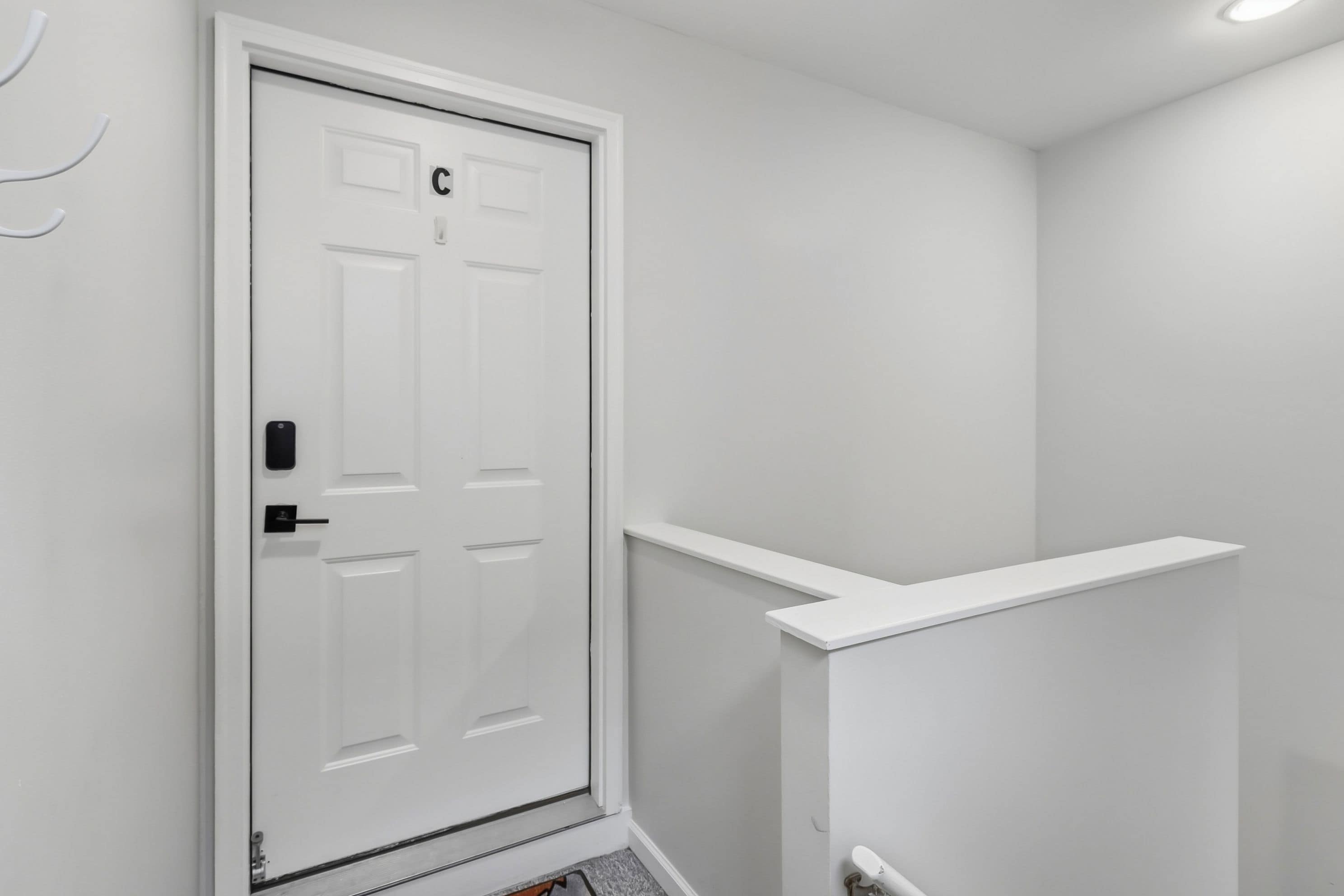 A white door with a keypad lock and a letter 'C' on it.