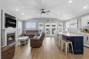 A spacious living room with a fireplace, a large sofa, and a television. - Downtown 3BR Top-Floor Condo w/ Balcony (Ocean City)