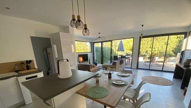 Una cocina moderna con comedor, ventanas amplias y vistas al exterior.