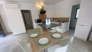 Una cocina moderna con comedor, que incluye una mesa de madera con individuales verdes, platos blancos y una silla blanca.