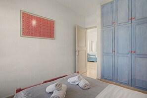 A bedroom with a bed, a wardrobe, and a framed picture on the wall. - Apartment 'Memories' with Balcony, Wi-Fi and Air Conditioning (Palekastro)