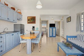 A spacious kitchen with a dining area, a living room with a sofa, and a hallway leading to other rooms. - Apartment 'Memories' with Balcony, Wi-Fi and Air Conditioning (Palekastro)