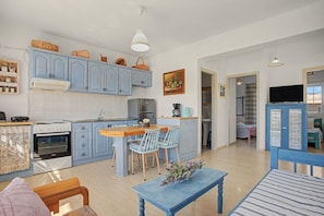 A compact kitchen with a dining area, a coffee machine, and a refrigerator. - Apartment 'Memories' with Balcony, Wi-Fi and Air Conditioning (Palekastro)