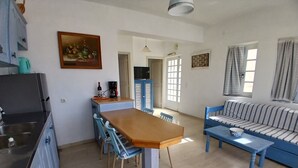 A compact living space with a dining area, a sofa, a kitchen with a sink, and a television. - Apartment 'Memories' with Balcony, Wi-Fi and Air Conditioning (Palekastro)