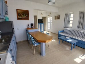 Un ambiente compatto con angolo ristoro, divano, cucina con lavello e televisione.