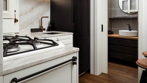 Una cocina moderna con estufa a gas, armarios blancos y piso de madera.