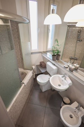 Une salle de bain moderne équipée d’une baignoire, de deux lavabos, de toilettes et d’un espace douche.