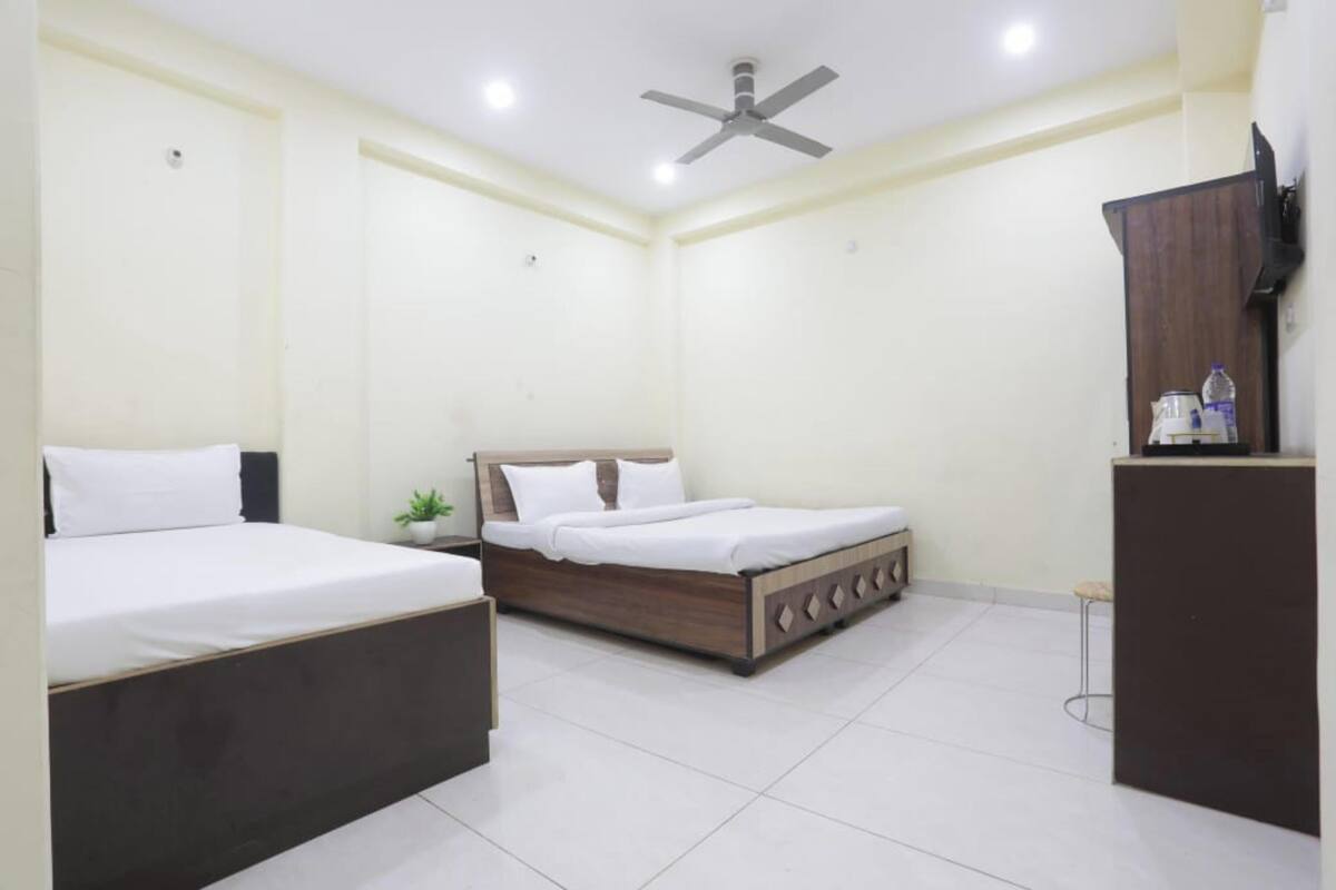 A bedroom with two beds, a ceiling fan, a nightstand, a small plant, and a cabinet.