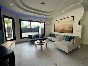 Ein modernes Wohnzimmer mit einer Couch, einem Couchtisch und einem großen Fenster.