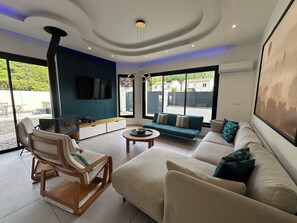 A modern living room with a sofa, armchair, and a fireplace. - Large 10-bedroom house - Jacuzzi - Garden - Near Bordeaux & Tram (Villenave-d'Ornon)