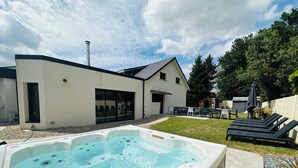 Una casa moderna con vasca idromassaggio, area salotto esterna e patio.