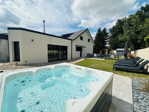 Ein modernes Haus mit Whirlpool, Sitzgelegenheit im Freien und einer Terrassenfläche.