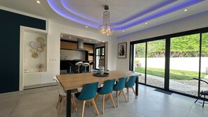 Una cucina moderna con zona pranzo, ampie finestre e un lampadario.