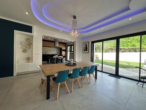 A modern kitchen with a dining area, large windows, and a chandelier. - Large 10-bedroom house - Jacuzzi - Garden - Near Bordeaux & Tram (Villenave-d'Ornon)