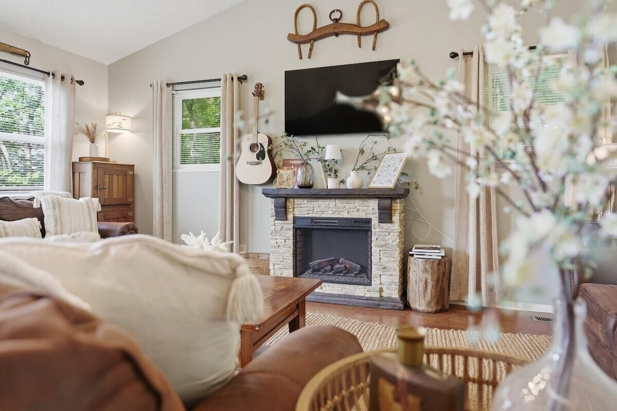 Un salon chaleureux avec une cheminée, un téléviseur fixé au-dessus, et un coin salon confortable avec un canapé et une table basse.