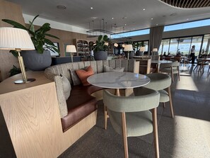 Ein stilvoller Lounge-Bereich mit einer Couch, runden Tischen und Topfpflanzen.