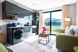Eine moderne Küche mit Geräten, ein Essbereich mit Tisch und Stühlen sowie ein großes Fenster mit Blick.