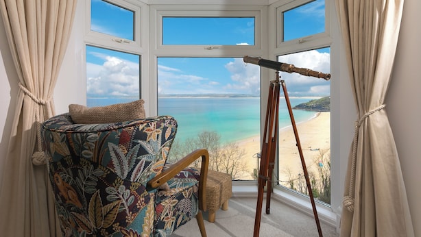A bay window with a view of a beach, a telescope, and a patterned armchair. - The Observatory | Boutique Coastal Retreat | Panoramic Sea Views | Beach 100m (St Ives)